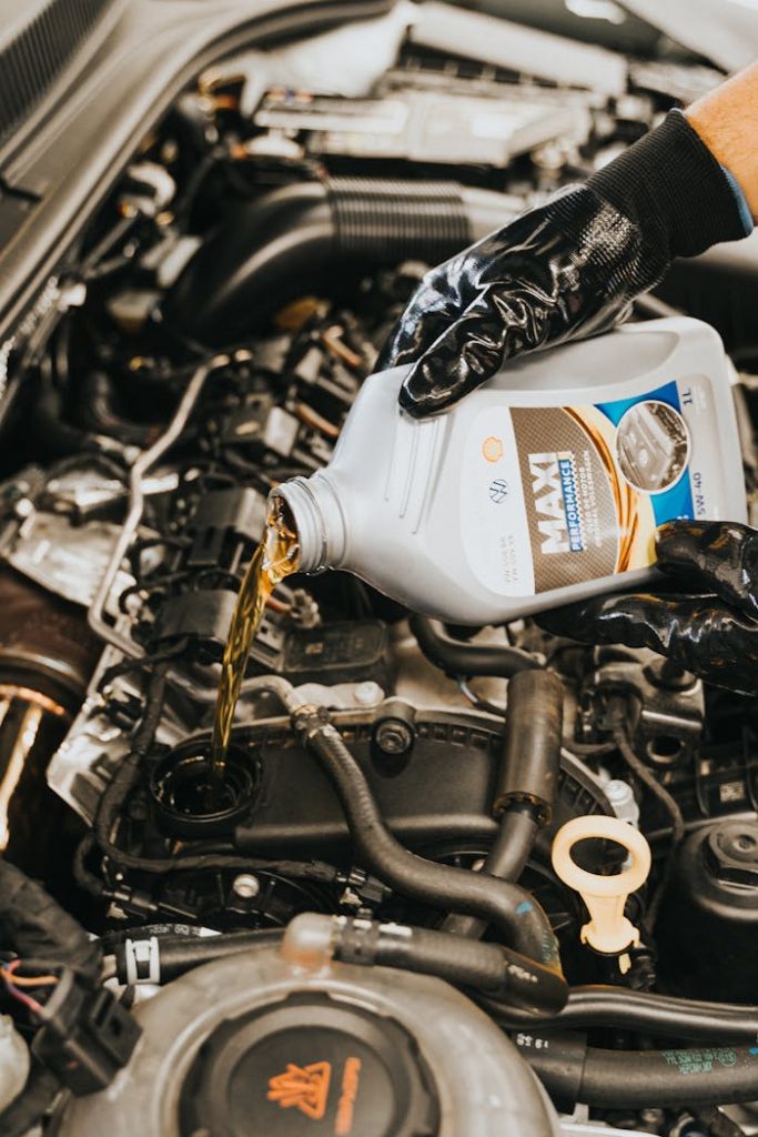 Close-up of mechanic pouring engine oil into car engine with gloved hands, showcasing automotive maintenance.