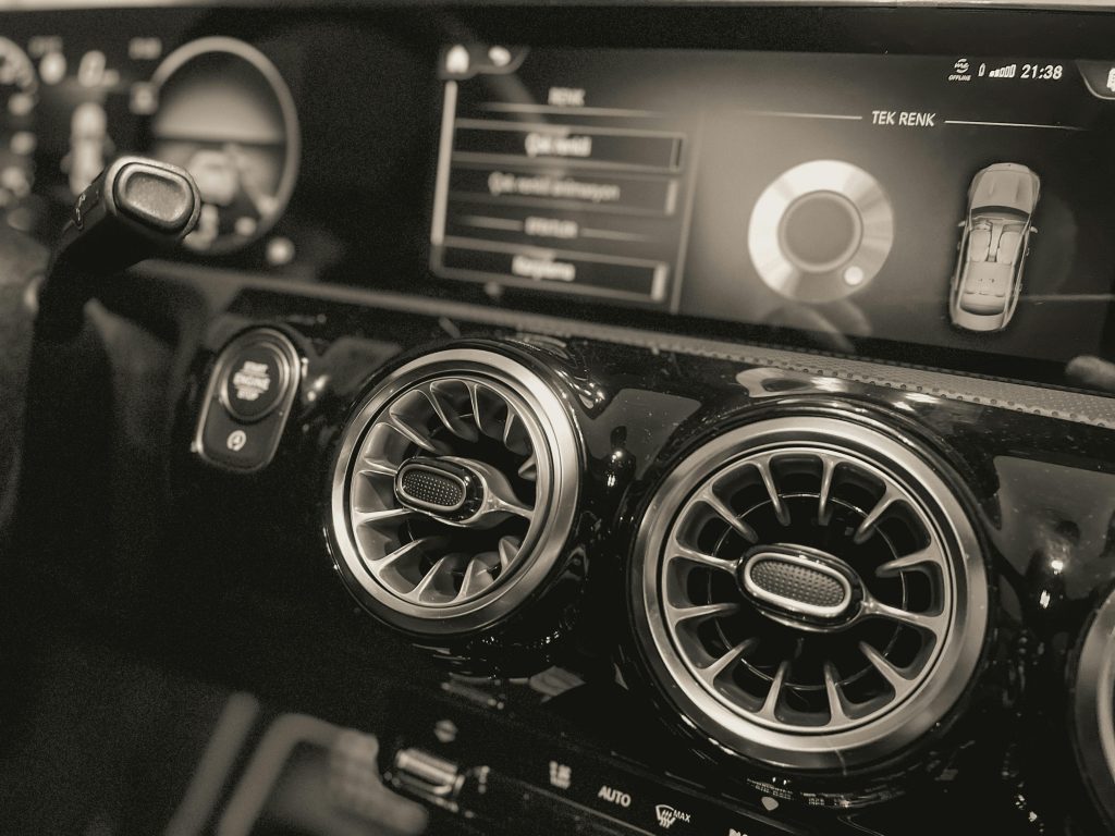 Close-up of Mercedes Benz dashboard with unique air vents in grayscale.